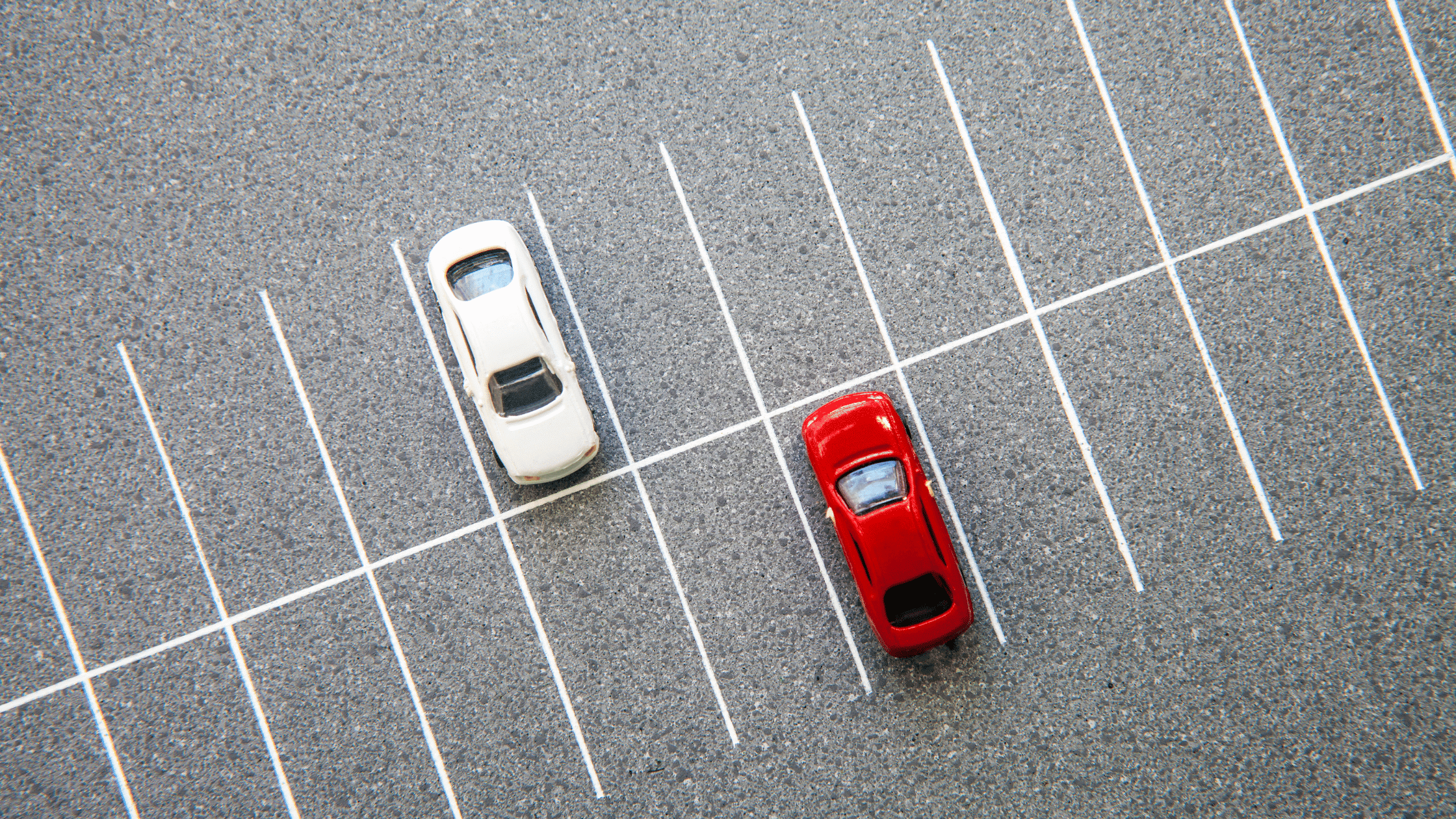 Aerial view of a parking lot, featuring a white car and a red car parked next to each other in designated spaces, showcasing efficient parking management.