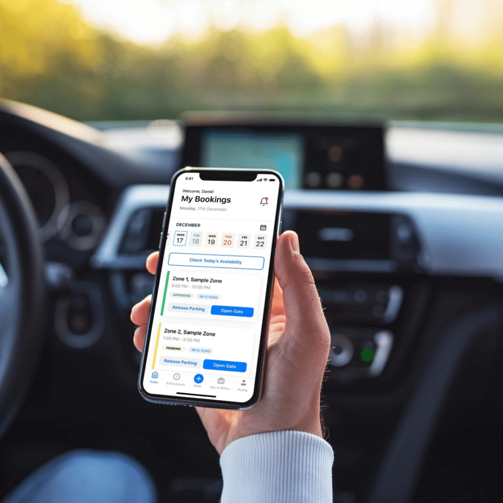 A person holding a smartphone displaying the Wayleadr app interface inside a car. The screen shows parking lot systems with bookings and availability in different zones, including visitor parking. The car dashboard and a blurred background are visible.