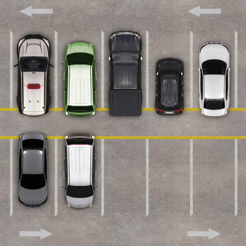 Aerial view of a parking lot with eight cars parked in two rows, showcasing efficient parking lot management. Seven spaces are empty, and arrows indicate the direction of traffic flow for visitor parking.