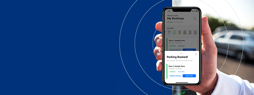 Hand holding a smartphone displaying a wayleadr parking booking confirmation screen with a car parked in the background.