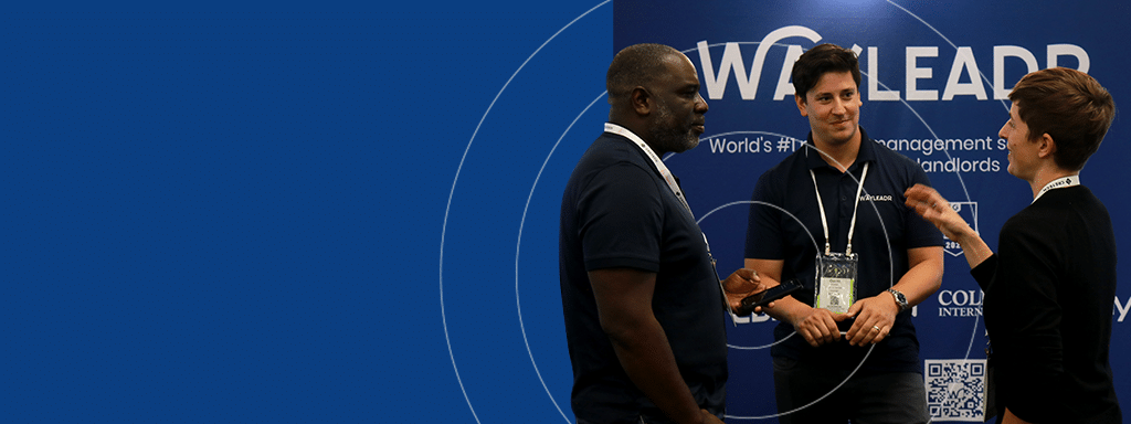 Three people engage in conversation at a WOA LEADR event, while discussions about visitor parking and effective parking lot management fill the room. The background features the event's logo and signage.