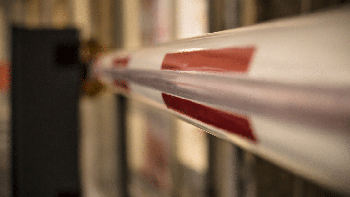 Close-up of a red and white barrier arm at a security checkpoint or entrance gate, expertly designed for efficient parking lot management, with a blurred background indicating an indoor or outdoor setting.