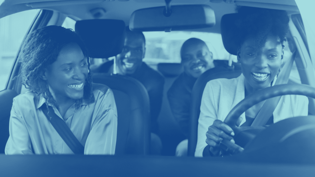 Four people are sitting inside a car, one driving and three passengers, all smiling and engaged in conversation as they navigate through the well-organized parking lot, expertly managed by the parking management team.