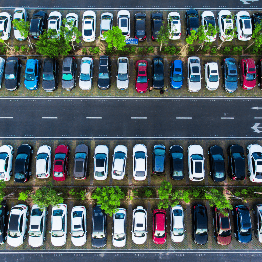 Aerial view of a parking lot with rows of parked cars and a tree-lined median strip, showcasing efficient parking management.