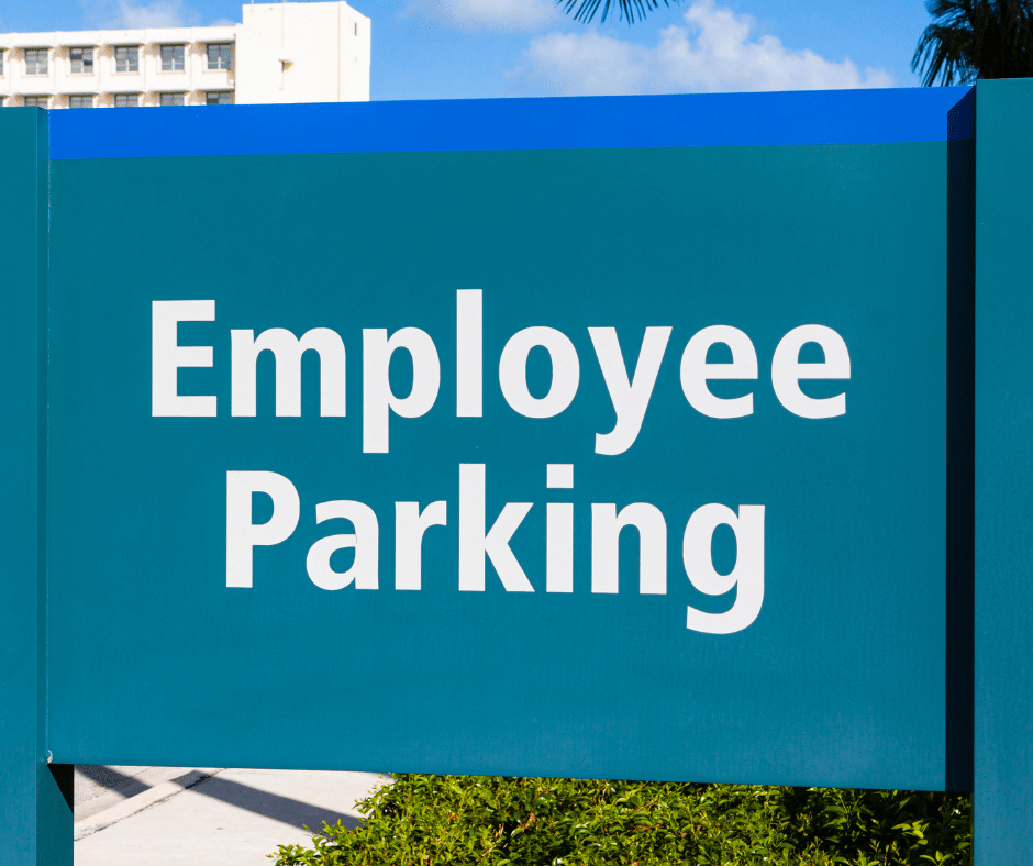 A large, green sign with bold white text reading "Employee Parking" stands out against a sunny blue sky backdrop, seamlessly integrating into the commercial parking lot systems.