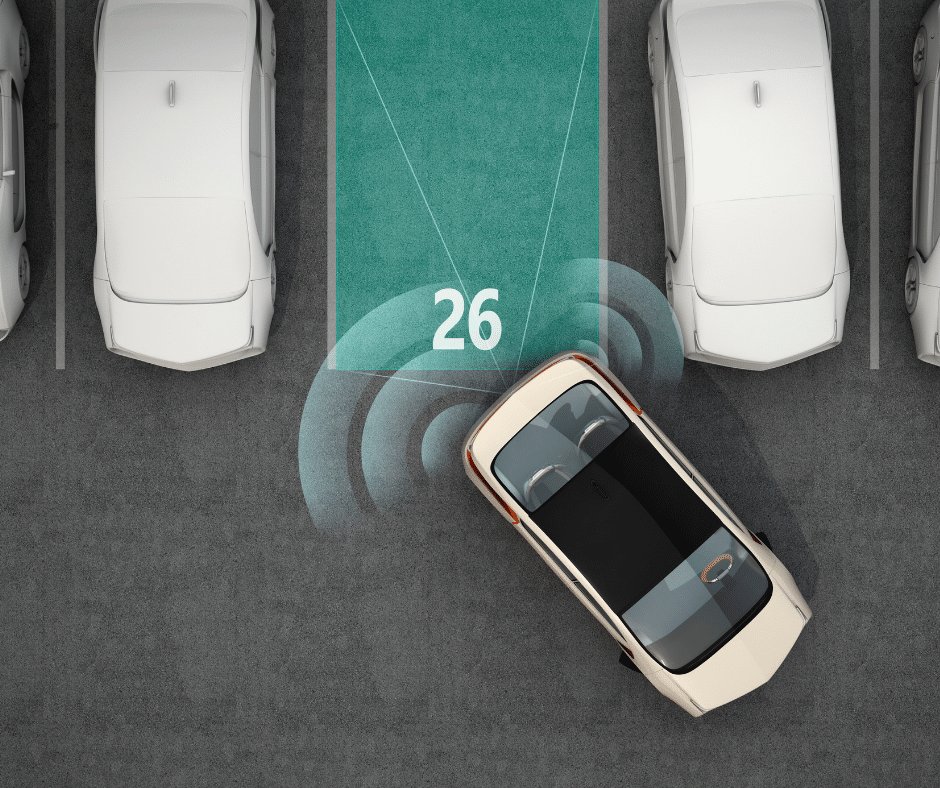 A car is in the process of parallel parking into a vacant spot labeled "26," surrounded by other parked cars. Sensor graphics, part of an advanced parking management system, indicate proximity detection.