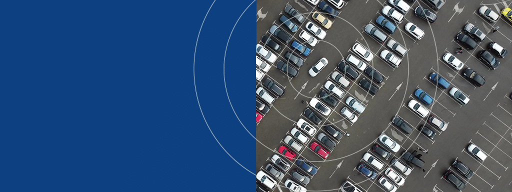 Aerial view of a parking lot filled with numerous cars in organized rows, highlighting effective parking management, adjacent to a solid blue area on the left.