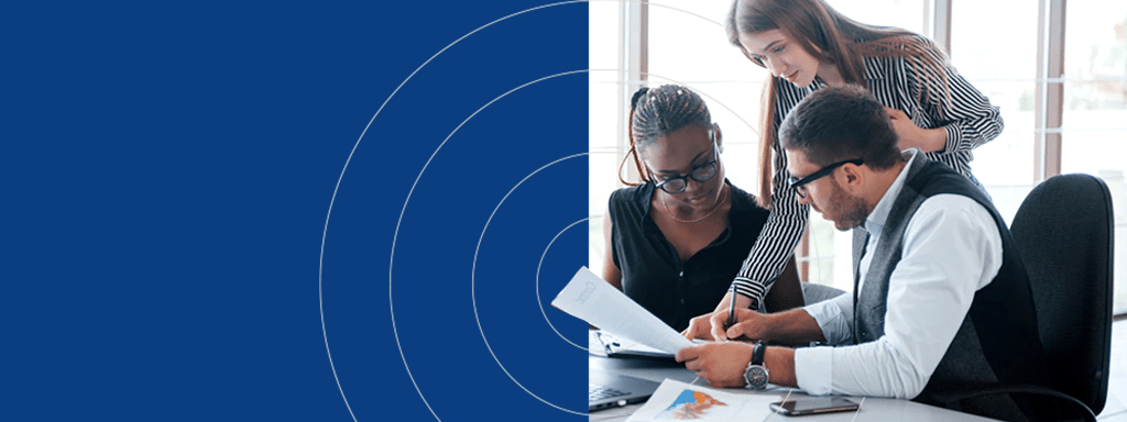 Three colleagues work together at a desk, reviewing documents and discussing content. A computer and charts are visible on the desk. The left side of the image features a blue background with circular patterns reminiscent of visitor parking signs.