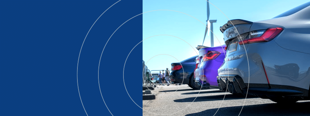 A lineup of parked cars with visible rear ends on a sunny day, highlighting an efficient commercial parking lot system. A wind turbine is visible in the background, seamlessly blending modernity and sustainability.