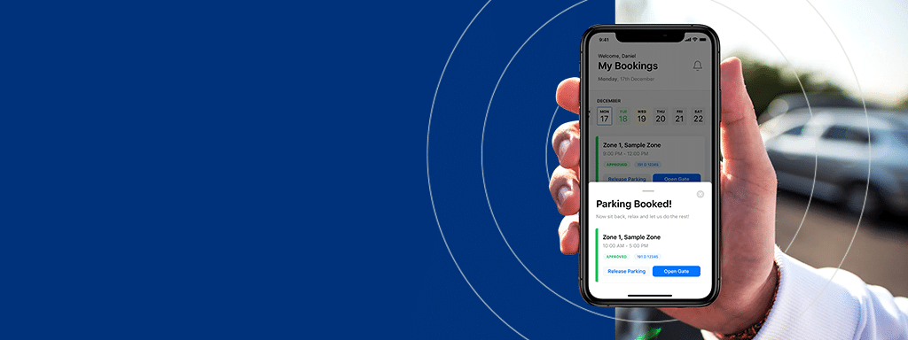 Person holding a smartphone displaying a parking booking confirmation screen against a blurred background with cars, showcasing an efficient parking management system.