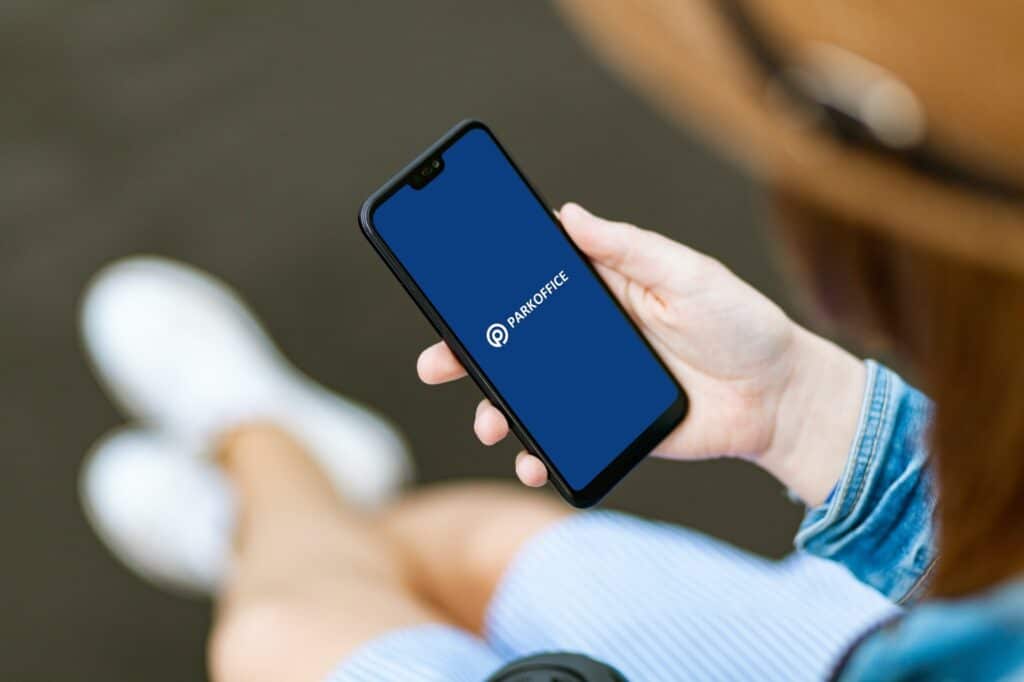 Person holding a smartphone displaying the ParkOffice app on the screen, showcasing advanced parking lot management features.