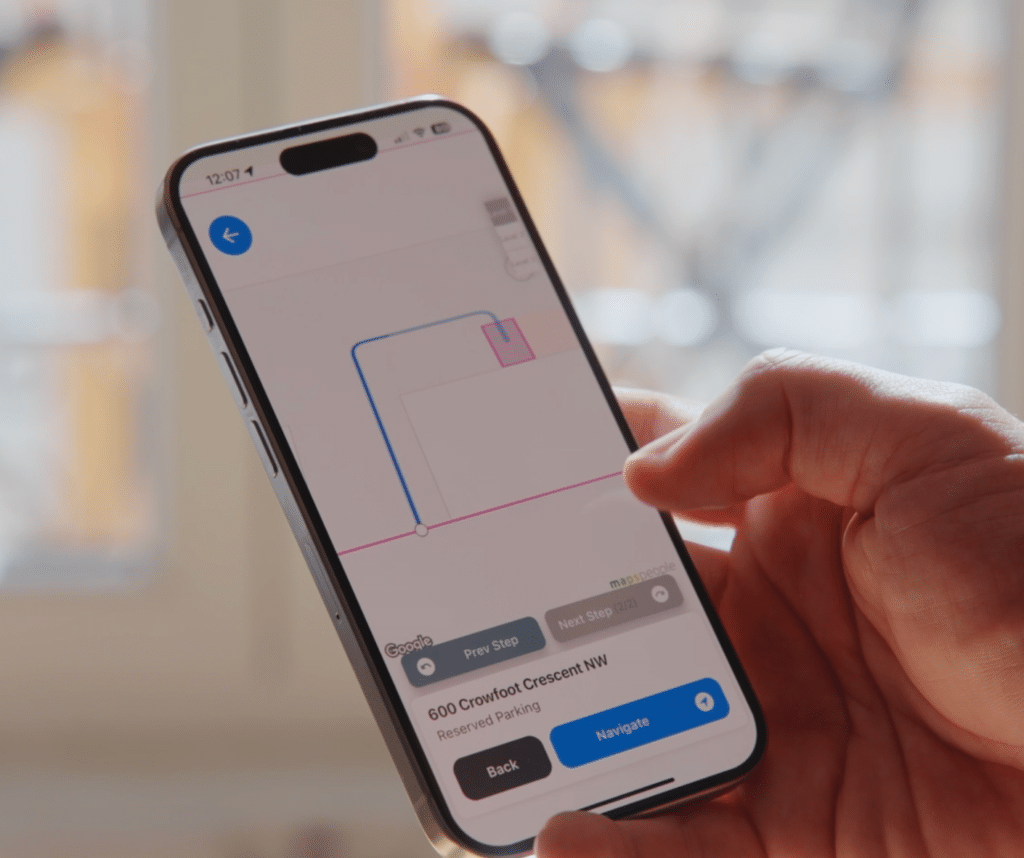 A hand holds a smartphone displaying a navigation app with a route leading to "600 Crowfoot Crescent NW," seamlessly integrated with Wayleadr's parking management system.