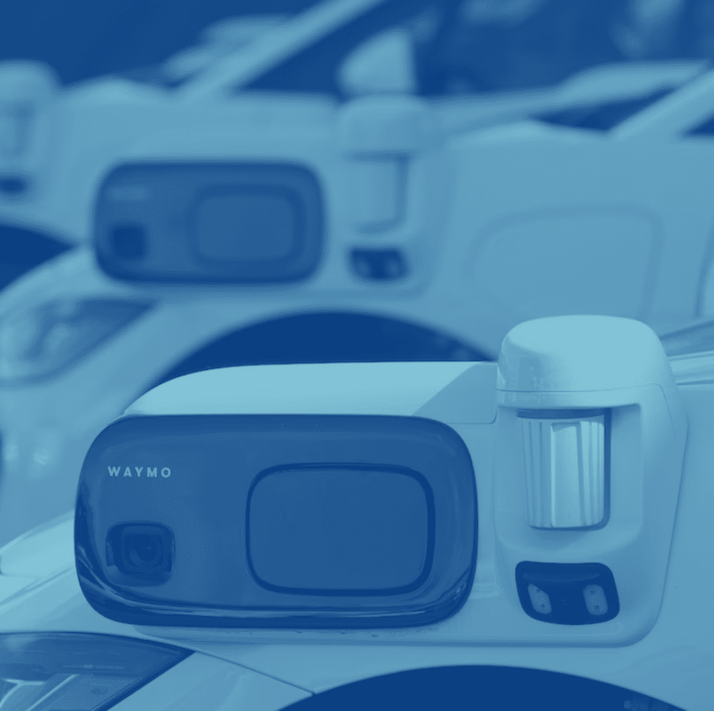 Close-up view of a row of Waymo self-driving cars equipped with various sensors and cameras, lined up in the visitor parking area. The white vehicles prominently display the Waymo logo, seamlessly integrating with advanced parking lot systems like Wayleadr.