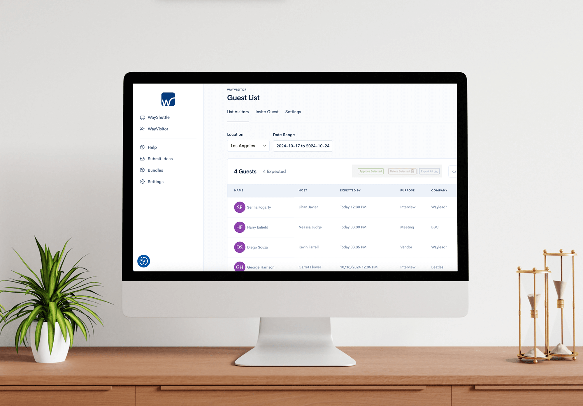 A computer screen displaying a guest list application with various tabs like help, submit ideas, bundles, and settings on the left. A plant and a decorative piece are on the wooden desk.