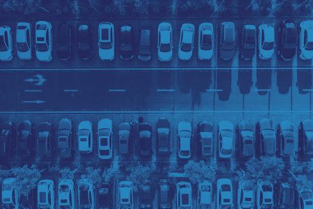 Aerial view of a parking lot featuring multiple rows of parked cars with a central road, showcasing efficient parking management.